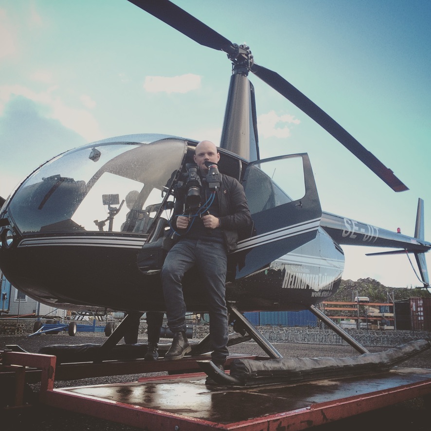 Daniel Joneström med kamerarigg framför en helikopter