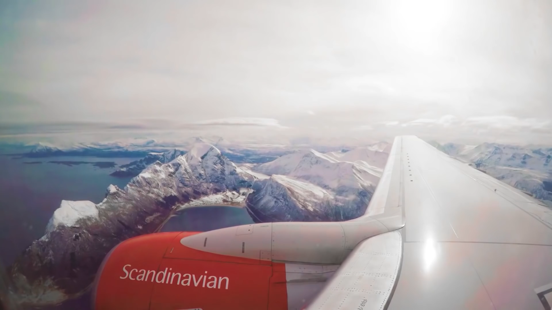 Flygplansvinge över snötäckta norska fjäll