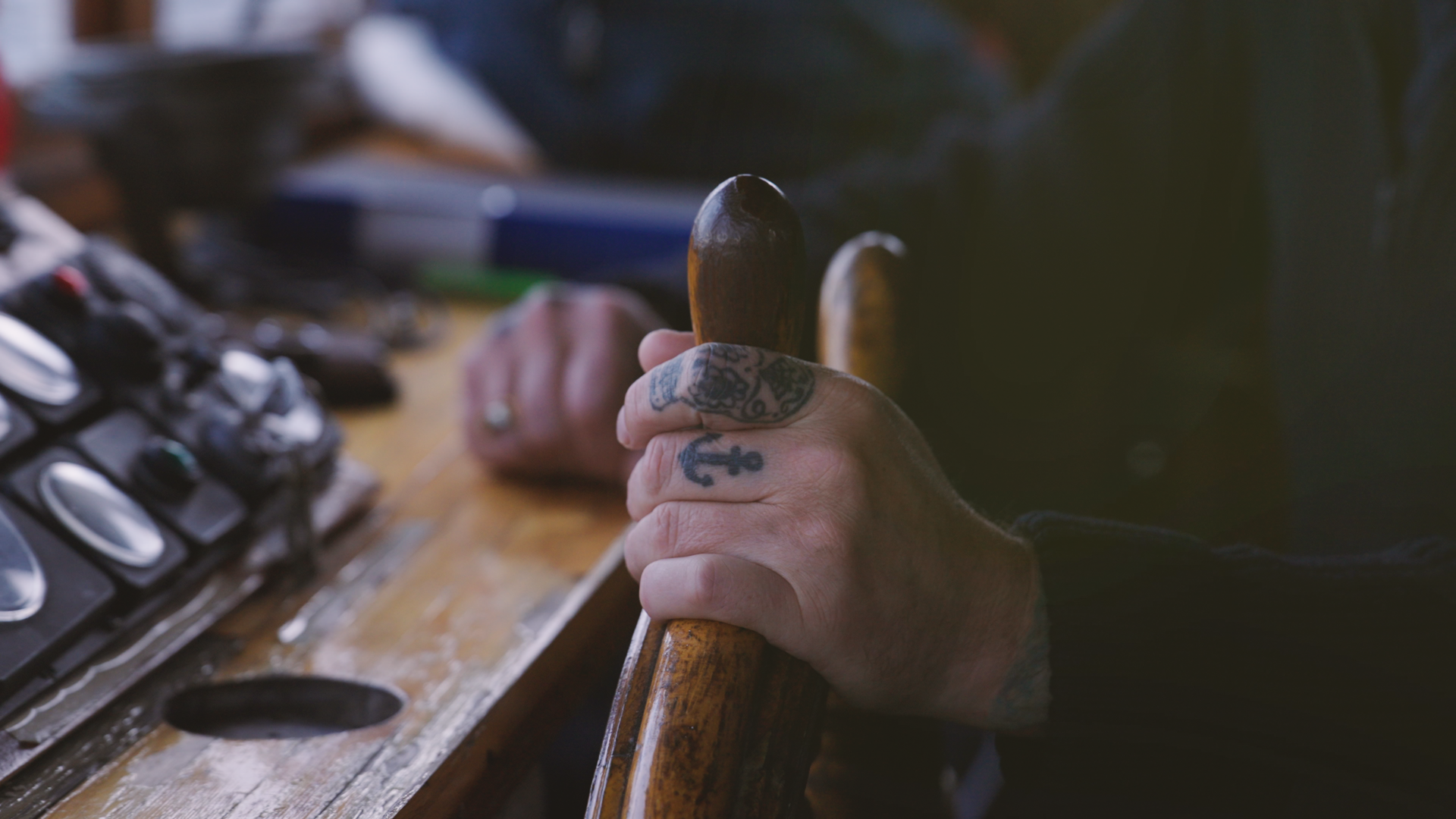 Tatuerad hand vid rodret i en styrhytt
